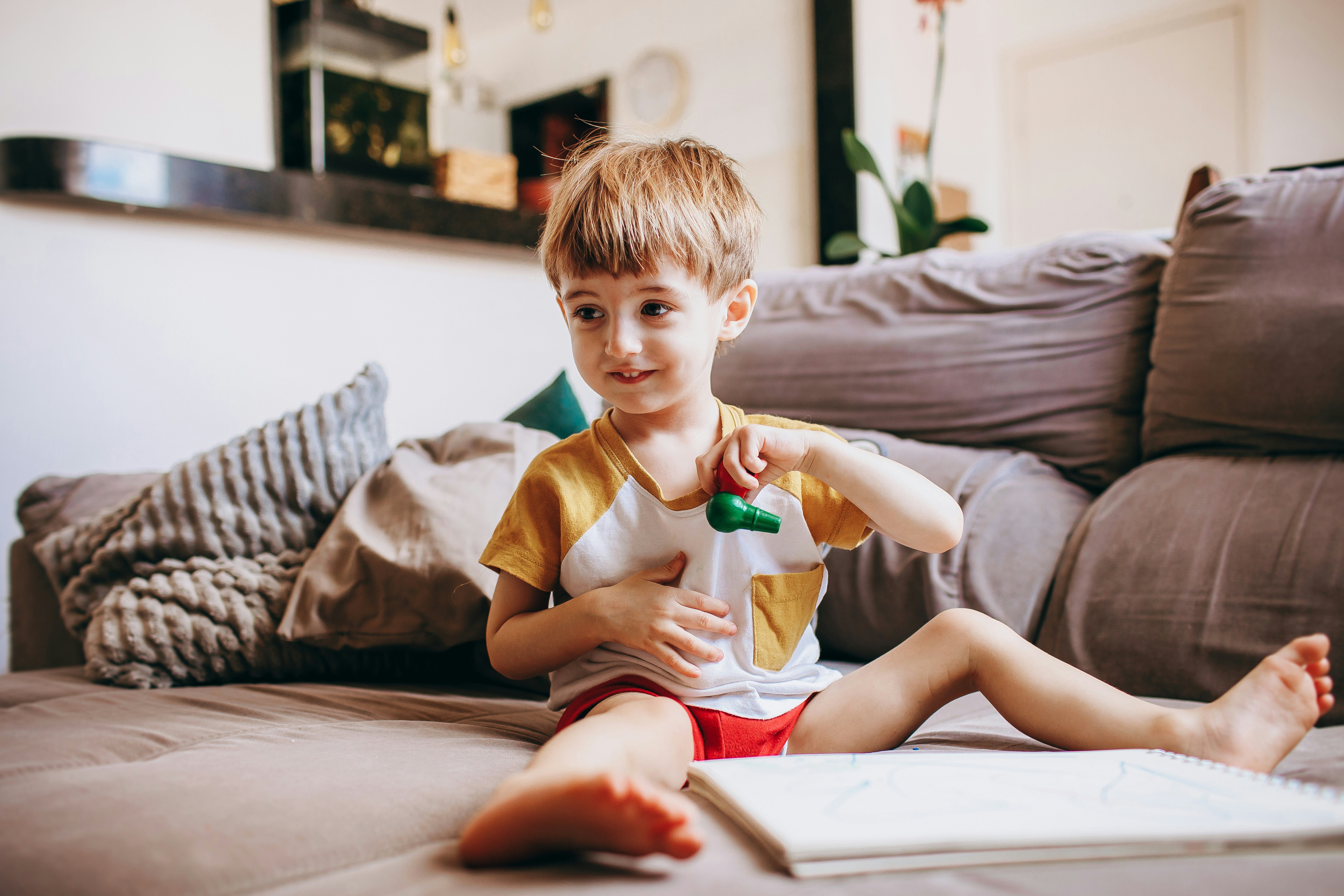 a young boy sitting on a couch with a book