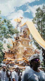 a group of people walking down a street next to a statue