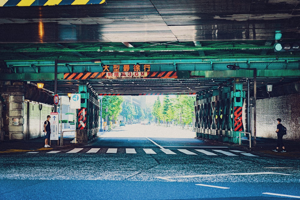 a man is standing under a green bridge