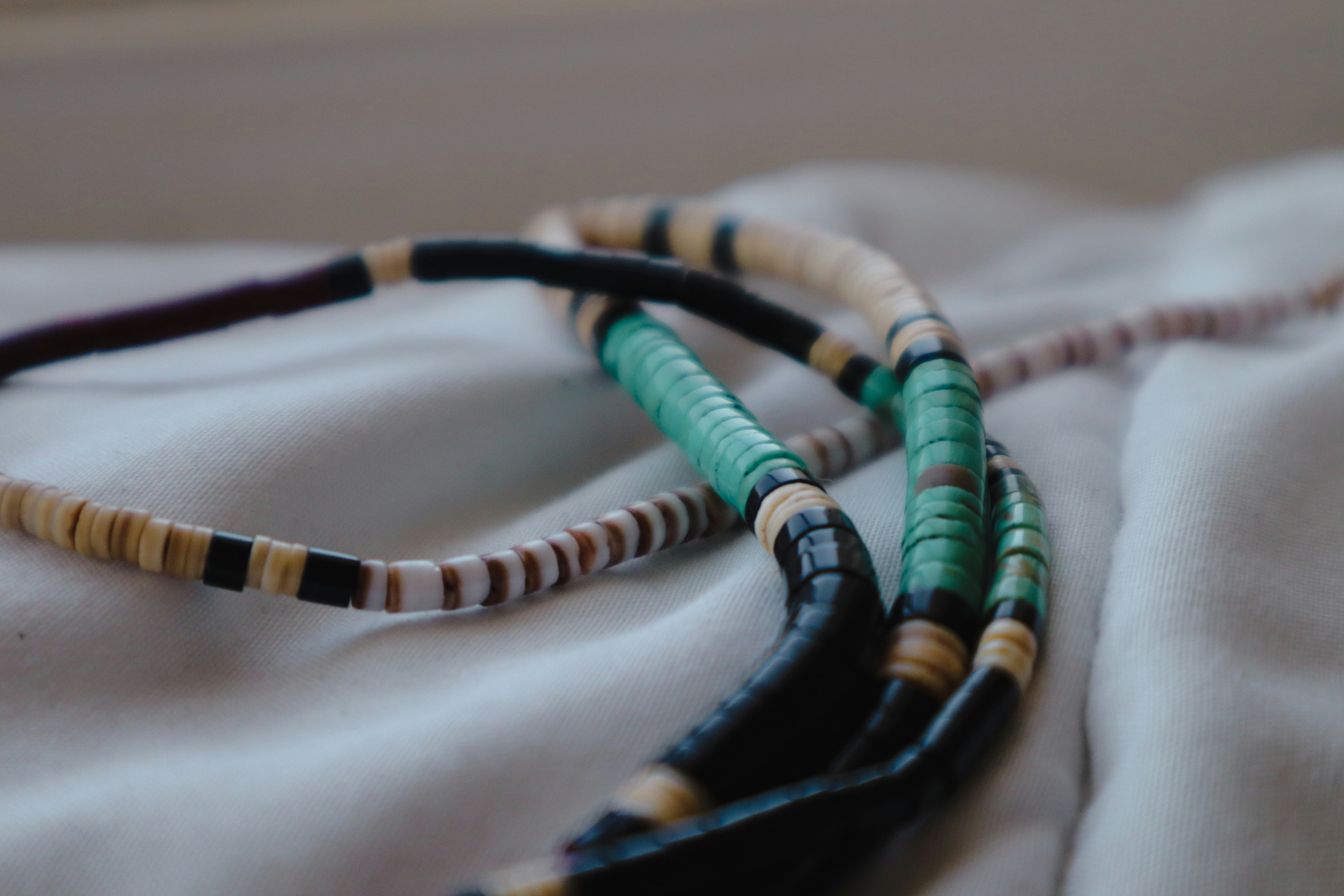 Colourful handmade African beaded necklace arranged on cream fabric in natural light