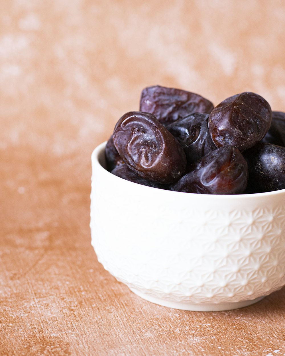 a white bowl filled with raisins on top of a wooden table