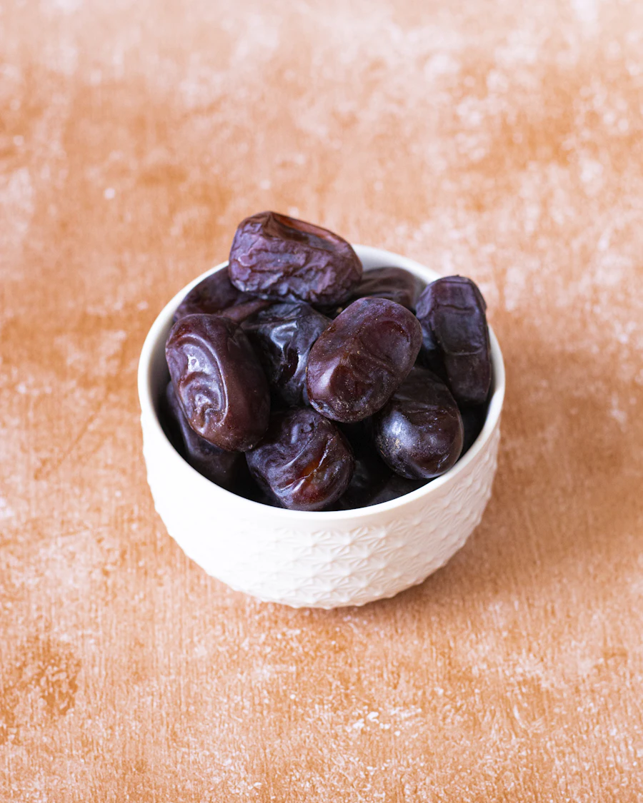 Dark, soft dates filling a small white bowl on a terracotta bench
