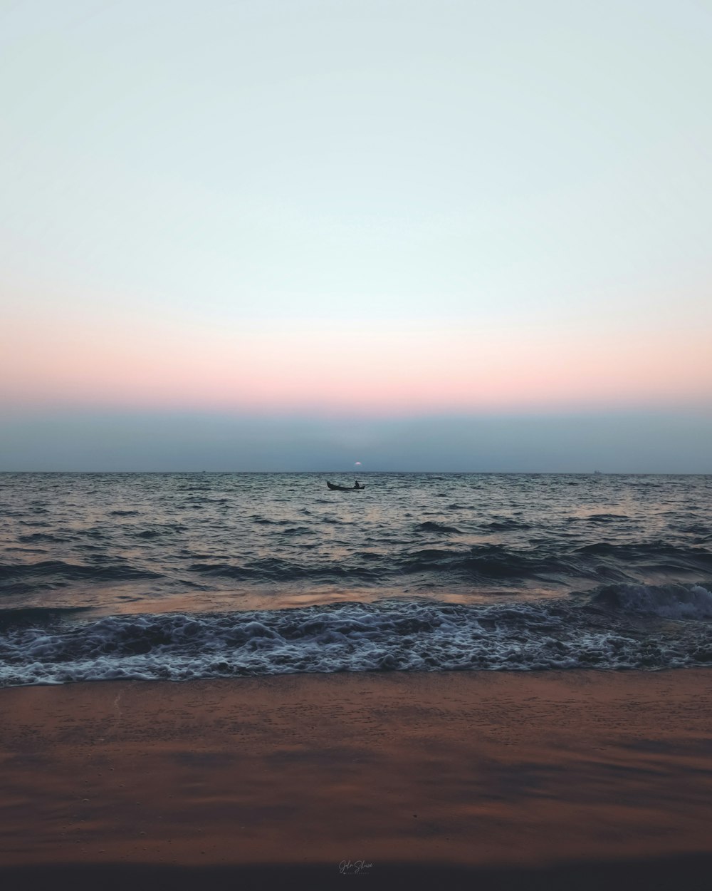 a boat is out in the ocean at sunset