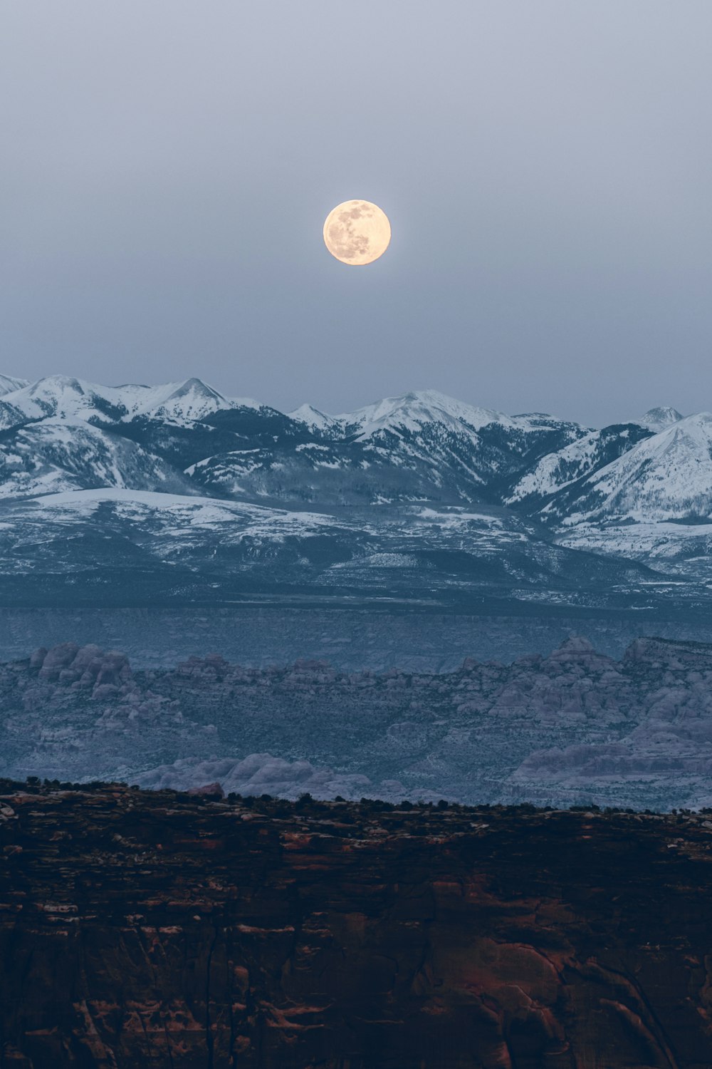 a full moon rising over a mountain range