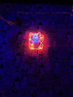 A cartoonish cat wearing sunglasses with a golden chain, glowing in neon red and gold colors.