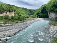 A scenic river flowing through a green valley in Lithuania.