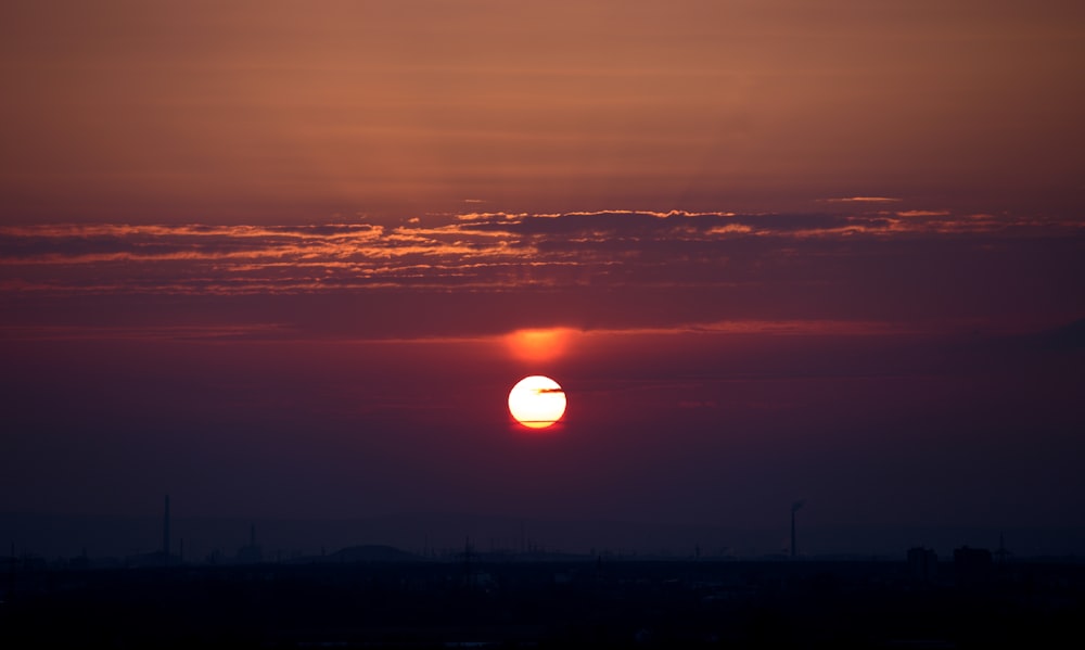 the sun is setting over the horizon of a city