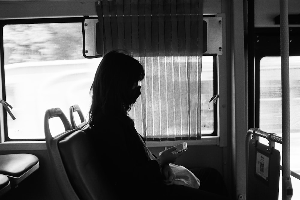 a woman sitting on a bus reading a book