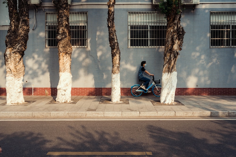 a man riding a bike down a street next to tall trees