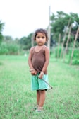 a little girl standing in a field with a stick