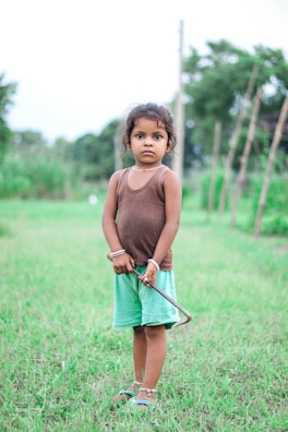 a little girl standing in a field with a stick