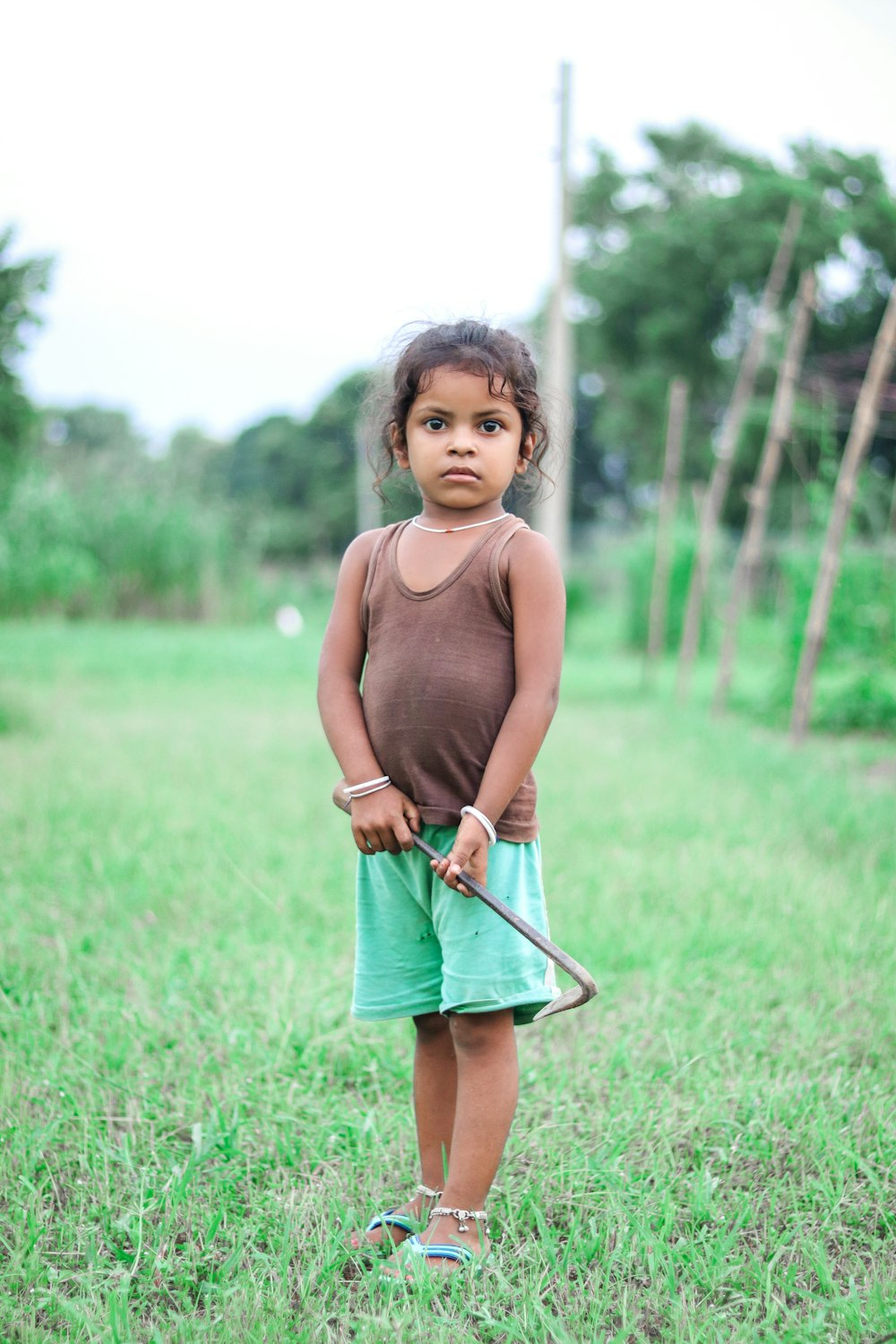 Una bambina in piedi in un campo con un bastone