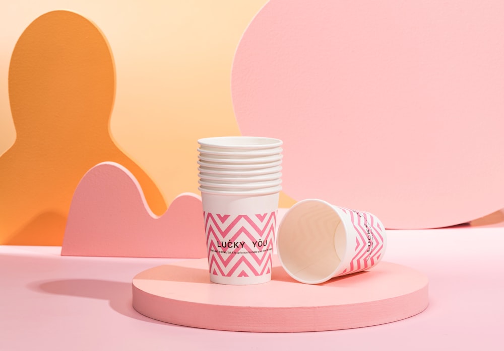 a stack of white cups sitting on top of a pink table