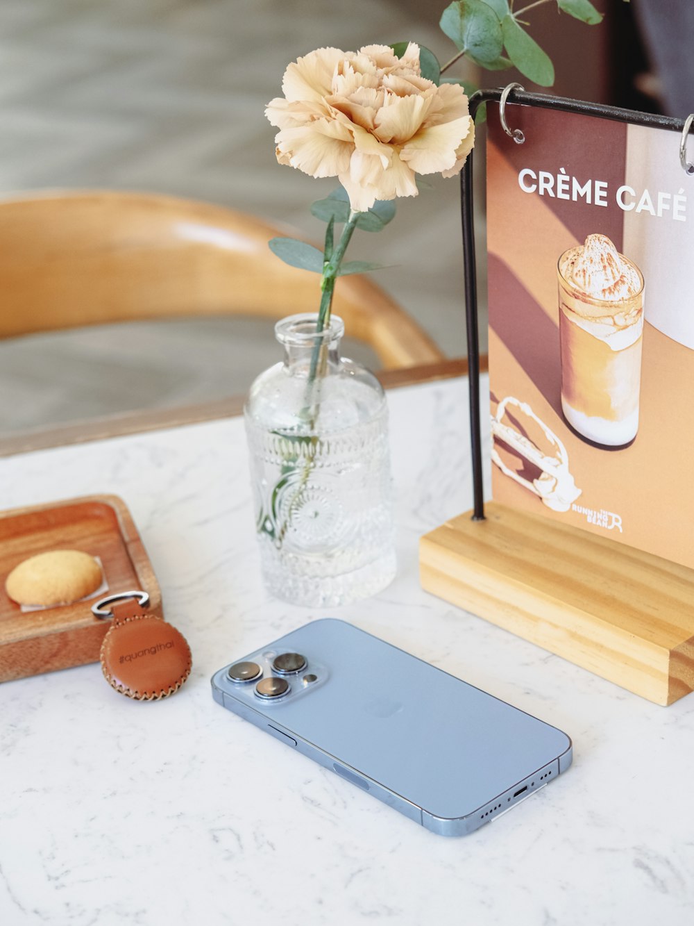 a table topped with a vase of flowers and a cell phone