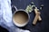 Close-up of a steaming cup of chai tea with floating cardamom pods and a rustic wooden table background.