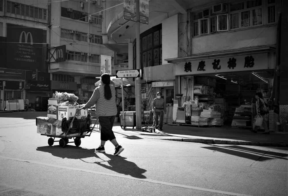 a woman pushing a cart full of boxes down a street