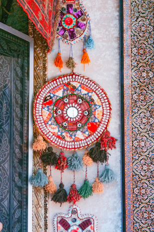 Close-up of a colorful fringe wall tapestry hanging above a comfy seating area.