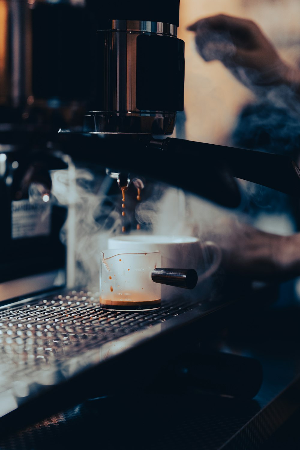 a cup of coffee being poured into a coffee machine