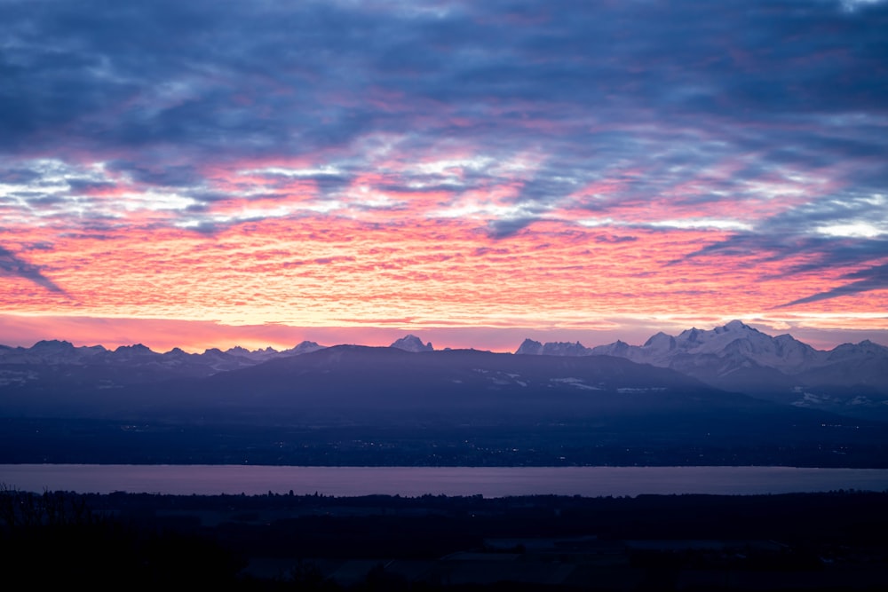 the sun is setting over a mountain range