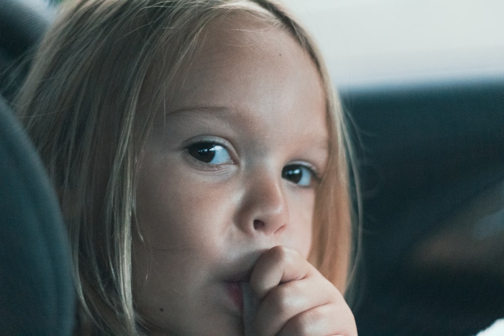 a little girl sitting in the back seat of a car