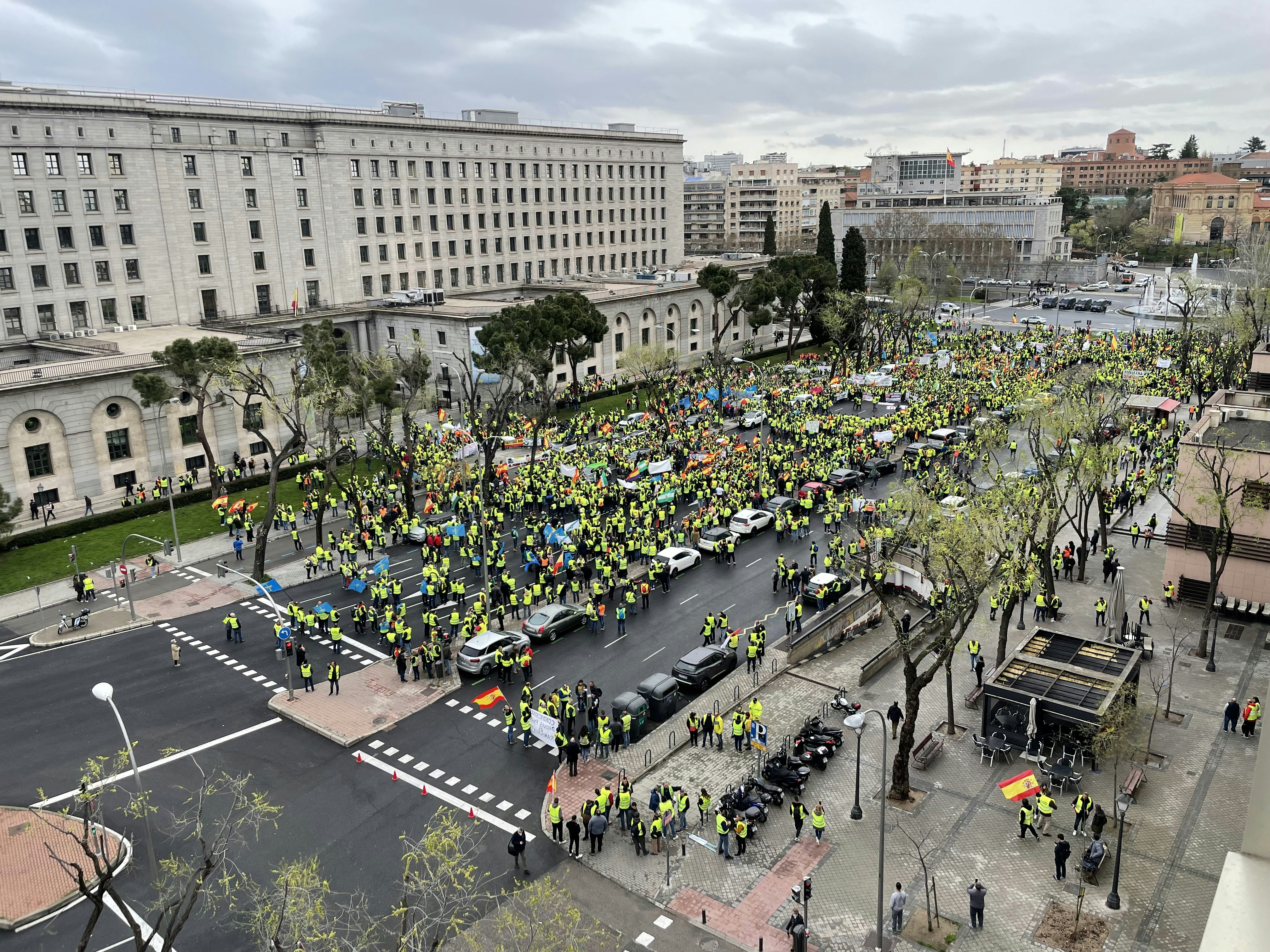 a large group of people standing in the middle of a street, Madrid, Spain. March 25. 2022. Protests by carriers of the "Plataforma Nacional por la Defensa del Transporte" (National Platform for the Defense of Transport) in front of the Ministry for Ecological Transition in Nuevos Ministerios in Madrid.