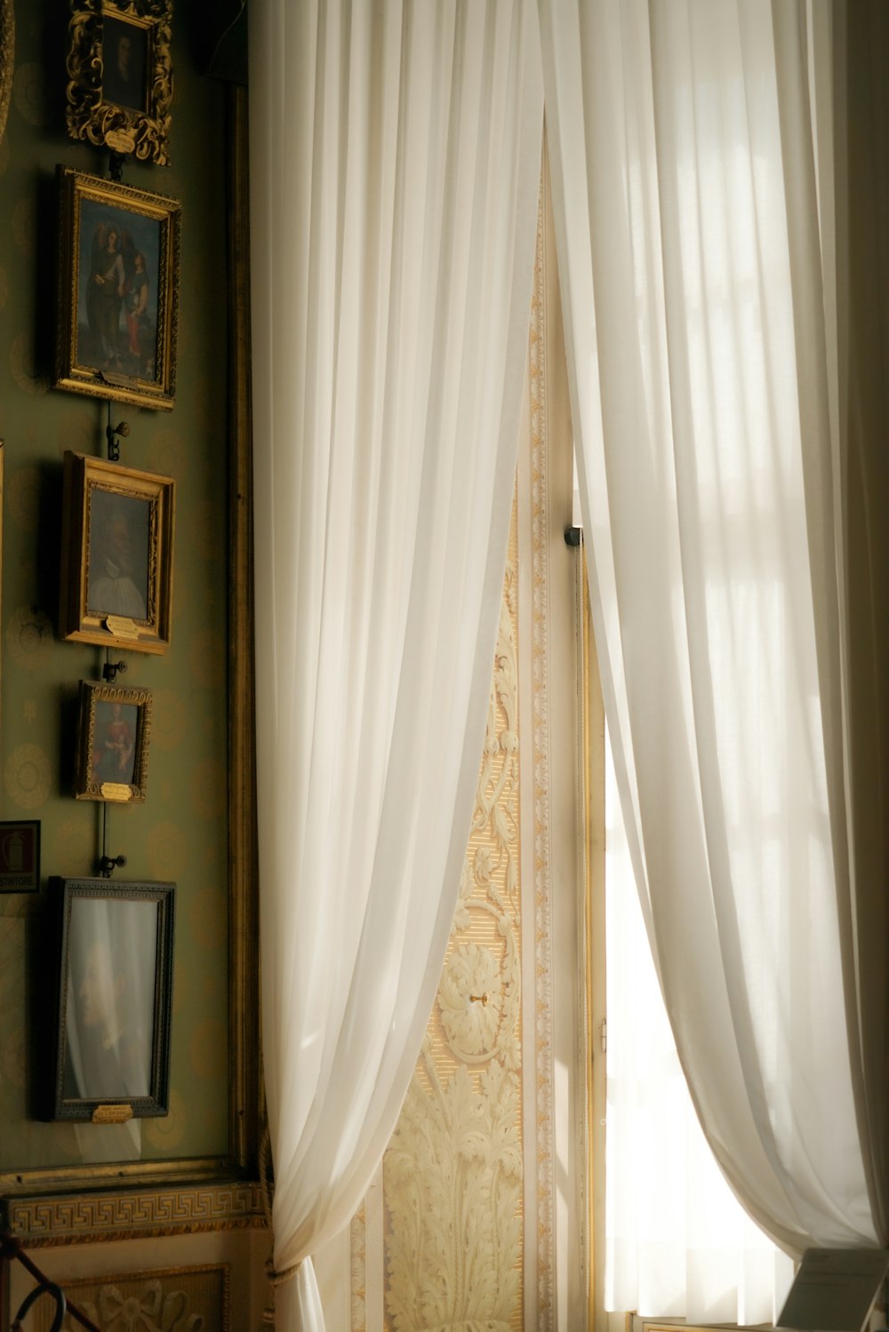 a bed sitting under a window next to a white curtain