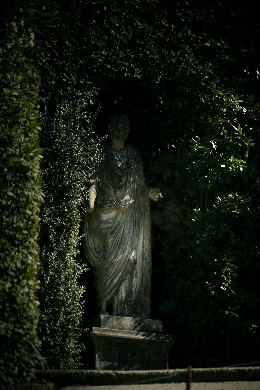 Una estatua de una mujer rodeada de vegetación