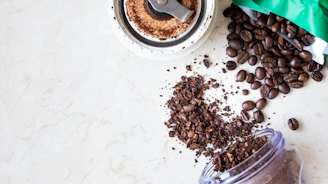 An open coffee pack with ground coffee spilling gently onto a textured surface.