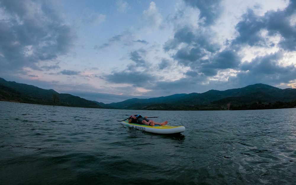 a man riding on top of a paddle boat on top of a lake