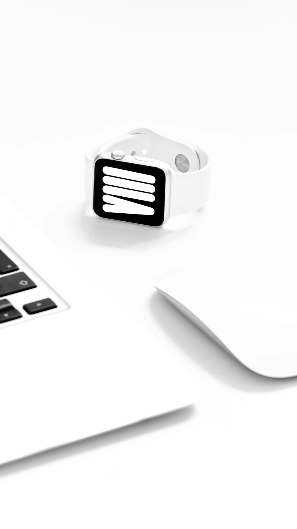 a white apple watch sitting on top of a laptop computer