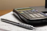 a calculator and a pen sitting on top of a piece of paper