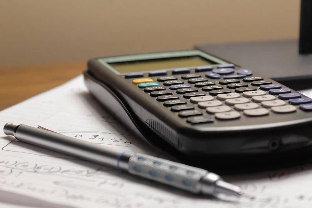 a calculator and a pen sitting on top of a piece of paper