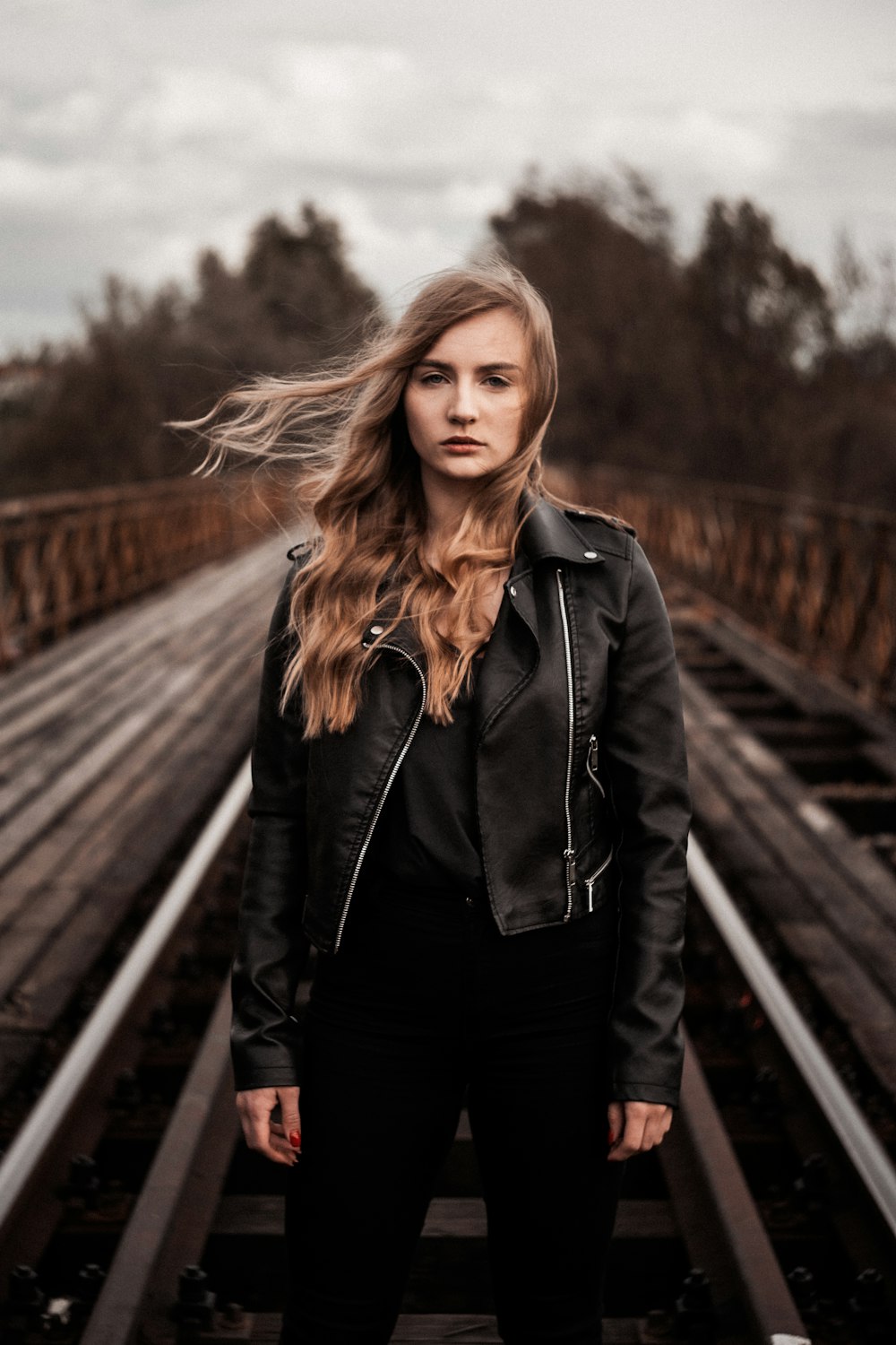 a woman with long hair standing on train tracks