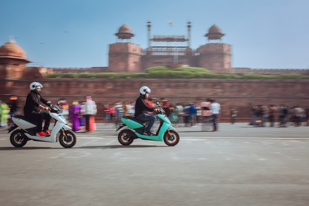 a couple of people riding on the back of scooters