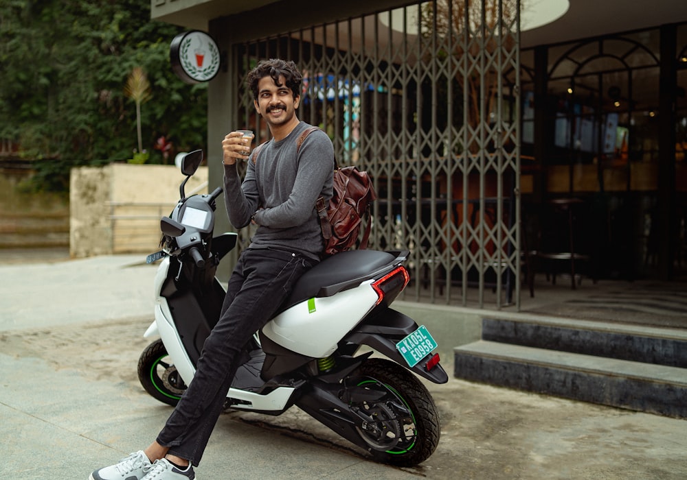 Un homme assis sur un scooter tenant un verre