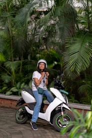 a woman sitting on a scooter in a tropical setting