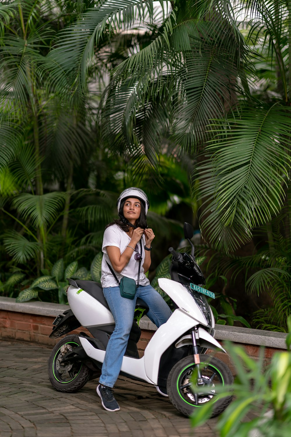 a woman sitting on a scooter in a tropical setting