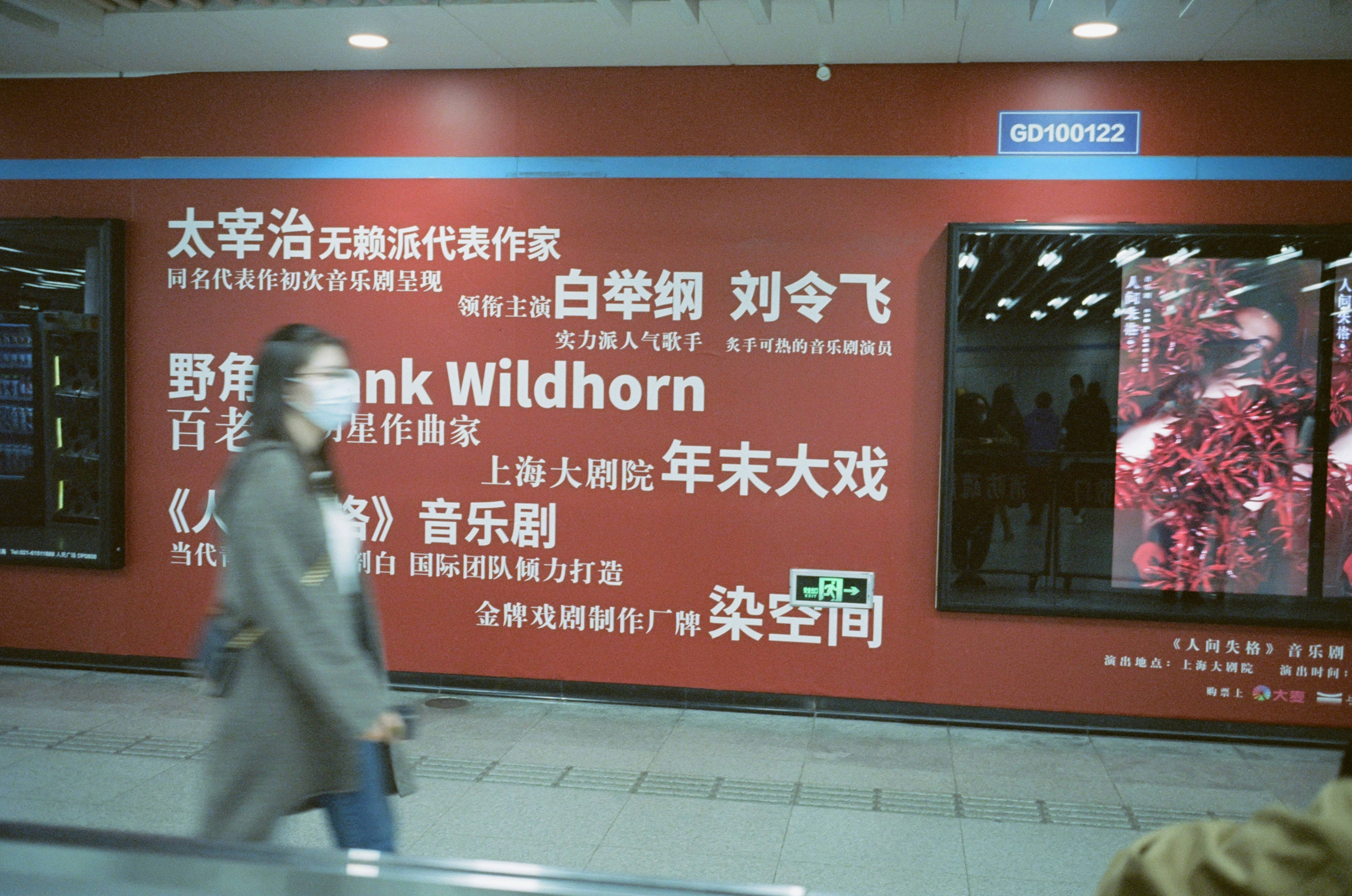 a man wearing a mask walking past a red wall
