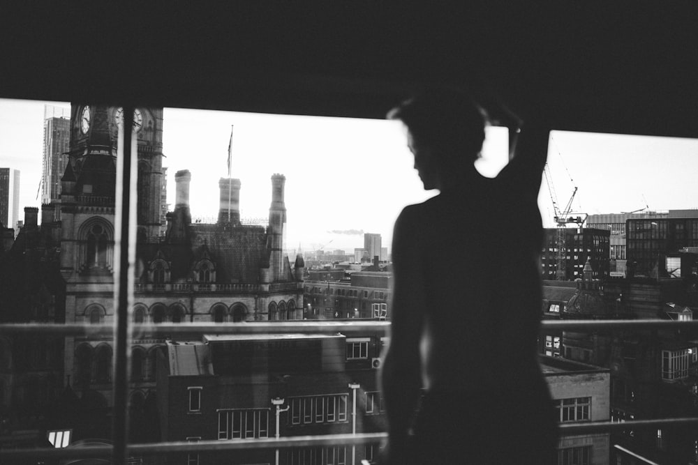 a person standing in front of a window looking out at a city