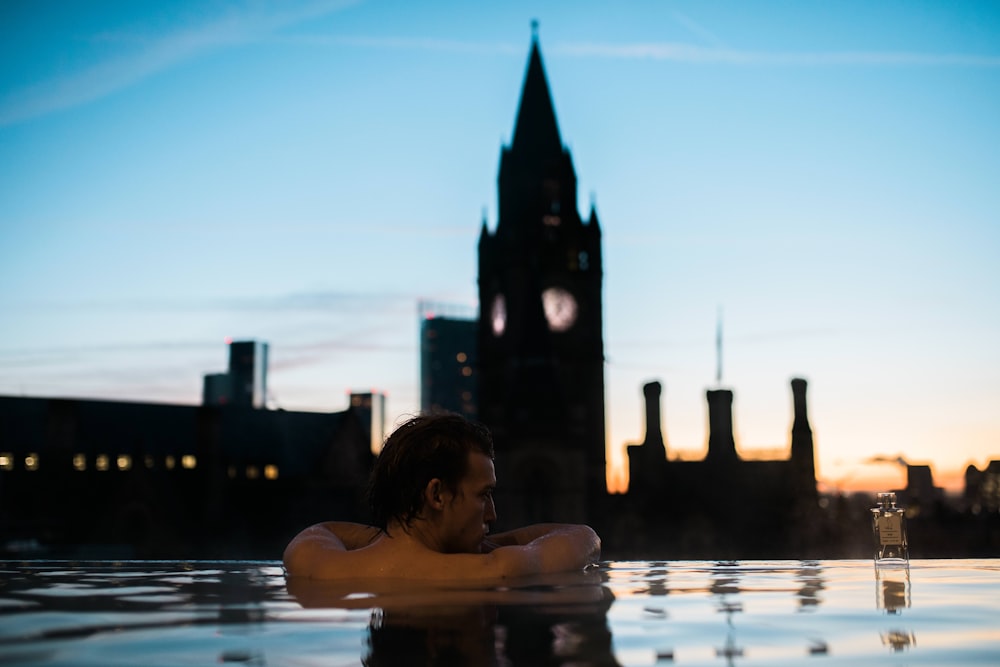 a man sitting in a pool in front of a tall building