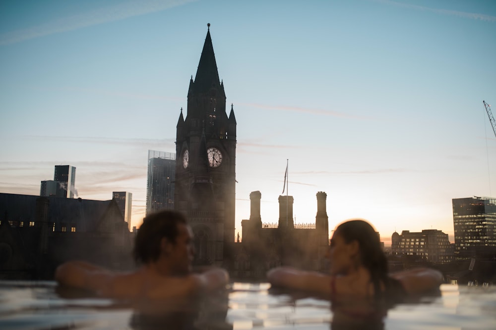 two people in a hot tub with a clock tower in the background