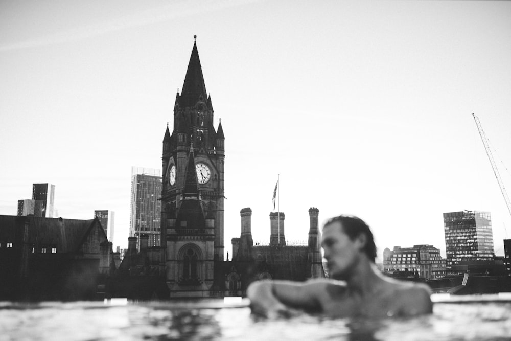 a man in a swimming pool with a clock tower in the background