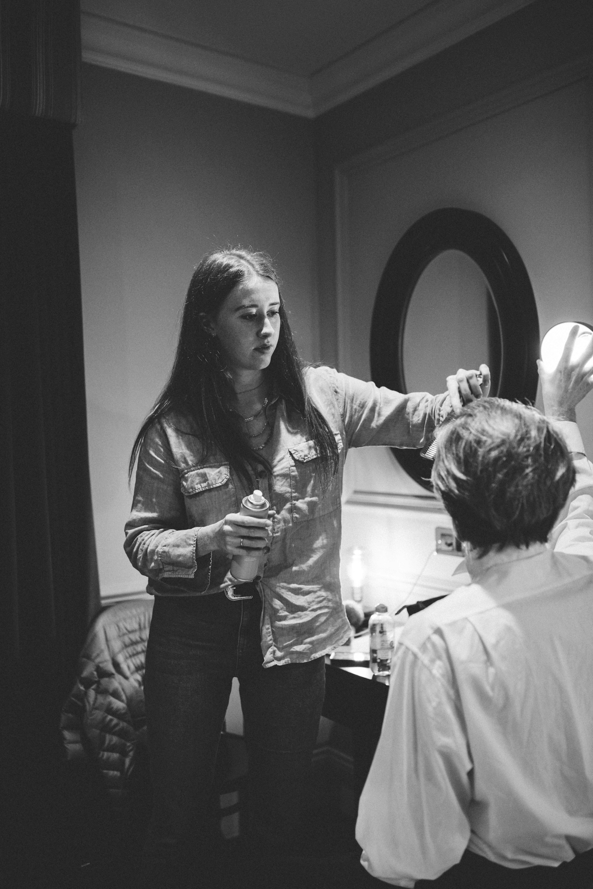 a woman standing in front of a mirror brushing her hair