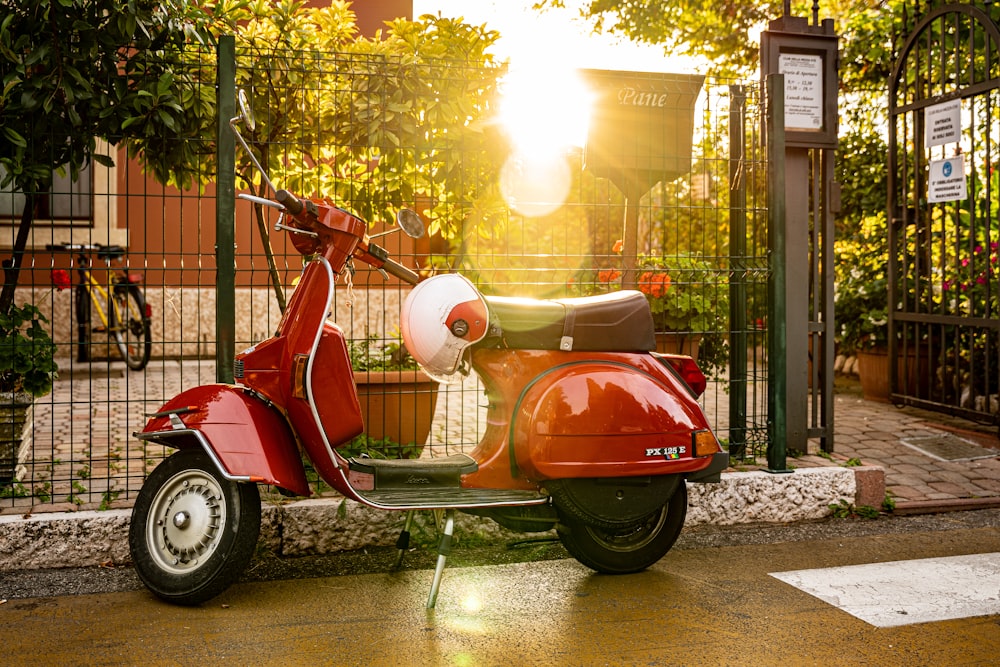 a red scooter parked in front of a gate