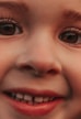 A close-up of a child's face is shown, highlighting the eyes, nose, and mouth. The focus is on the expressive eyes and a friendly smile, accentuated by long eyelashes and soft skin tones.