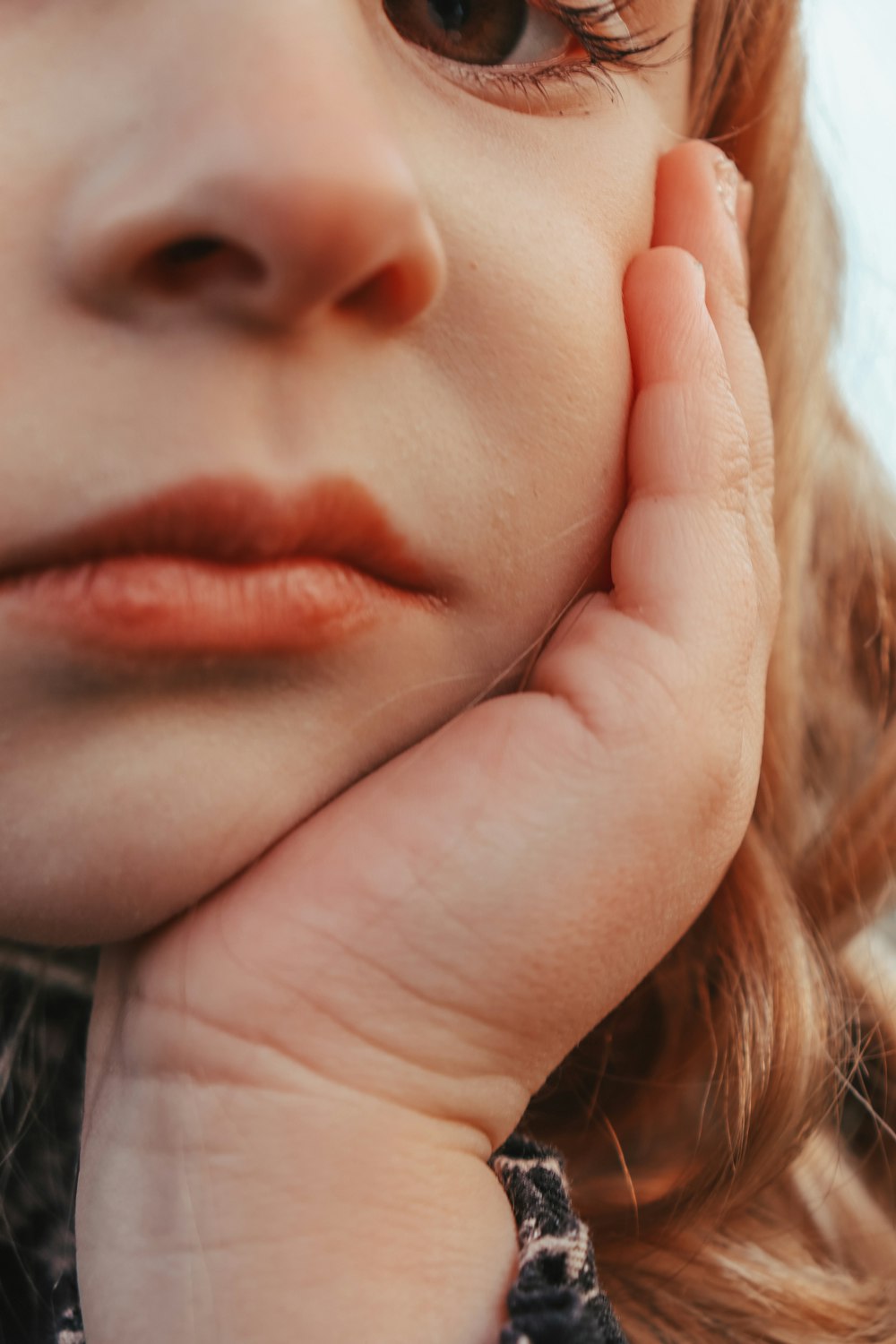 a close up of a child's face with her hand on her chin