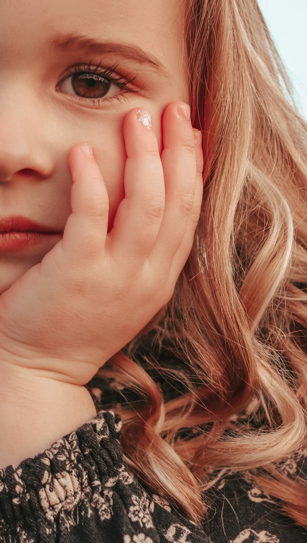 a close up of a child holding her hand to her face