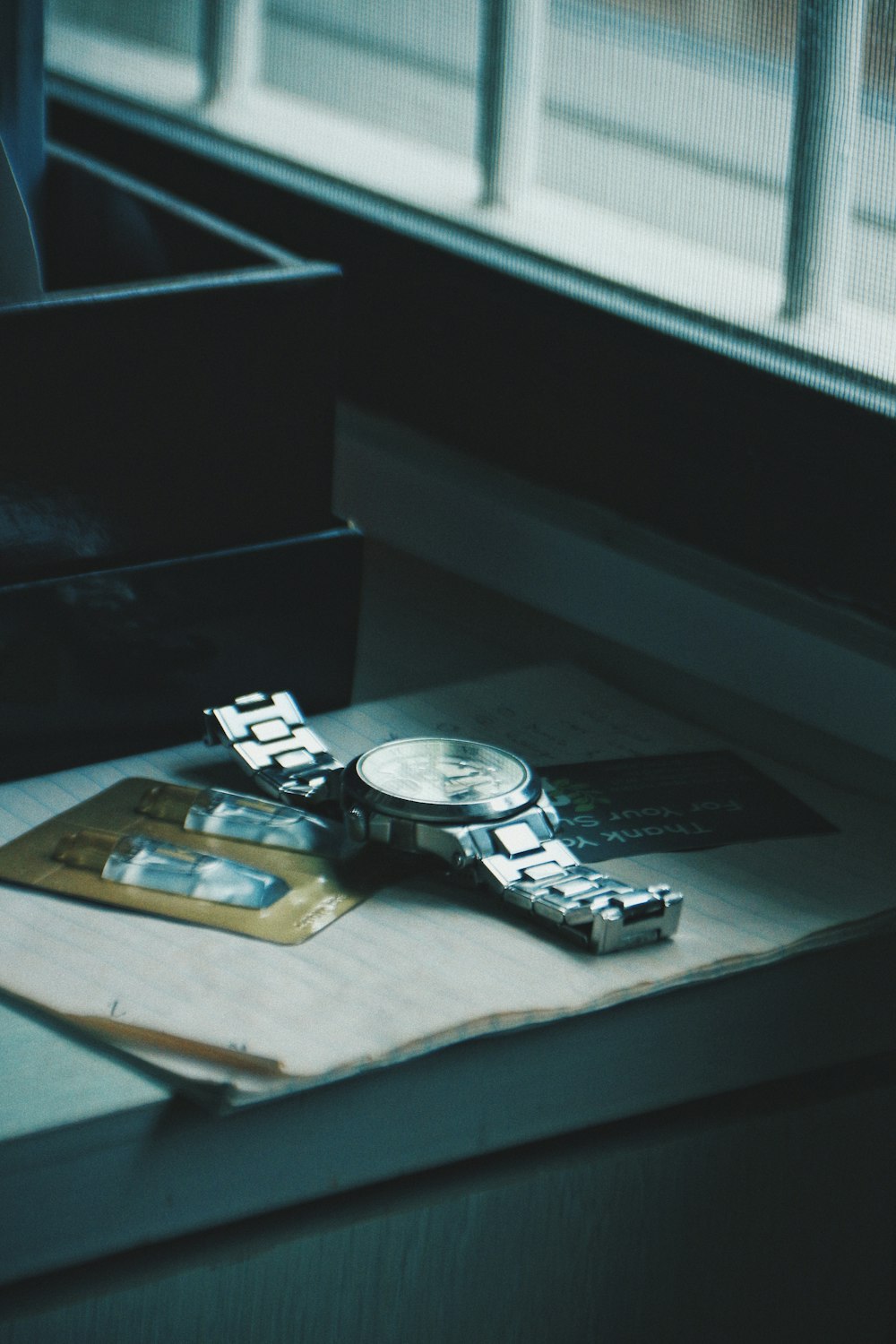 a watch sitting on top of a piece of paper next to a window