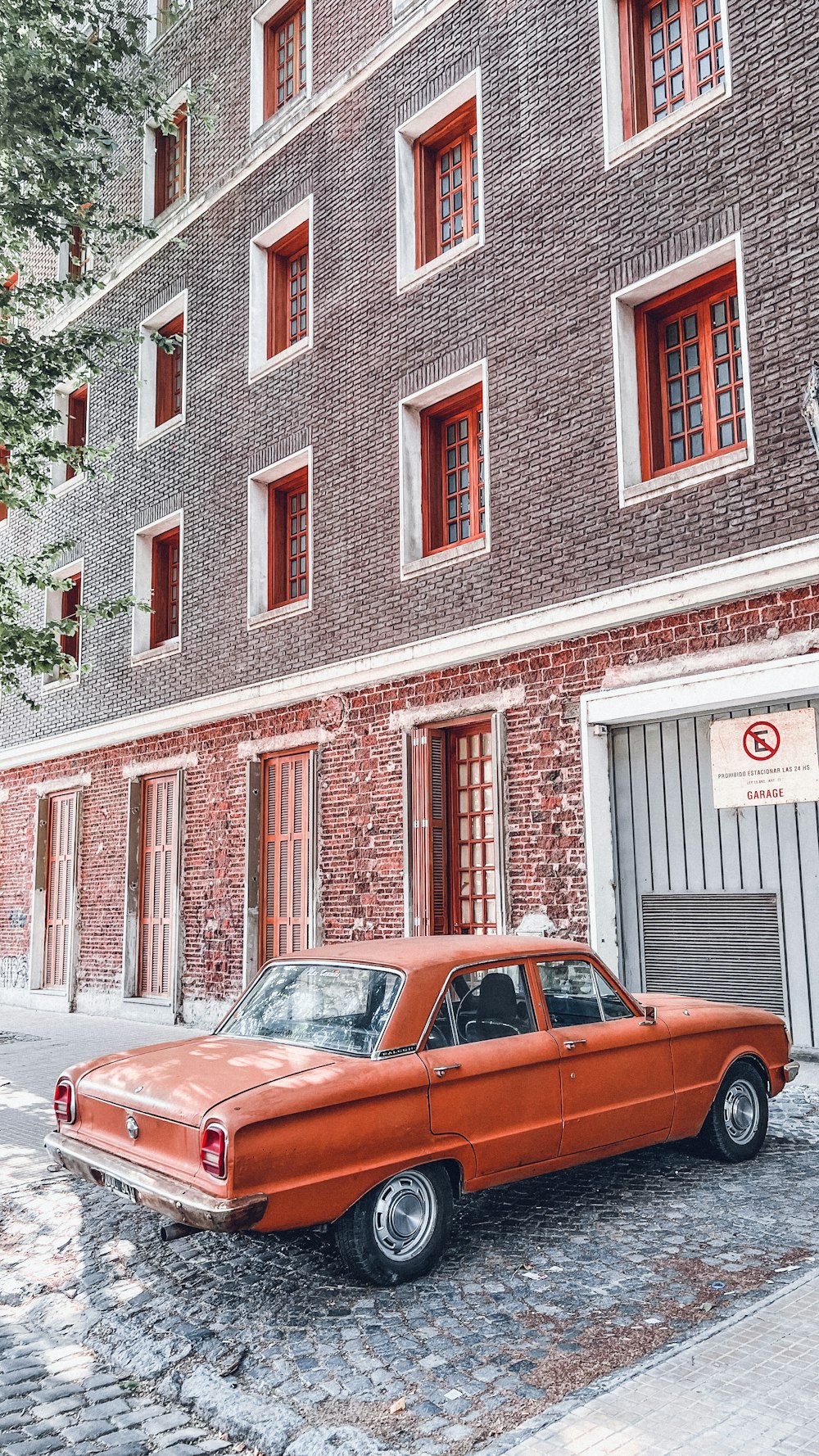 an orange car parked in front of a brick building