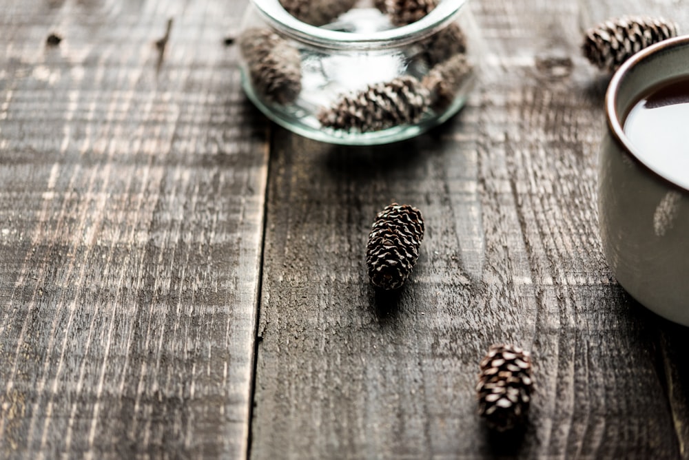 a glass of milk and some pine cones on a table